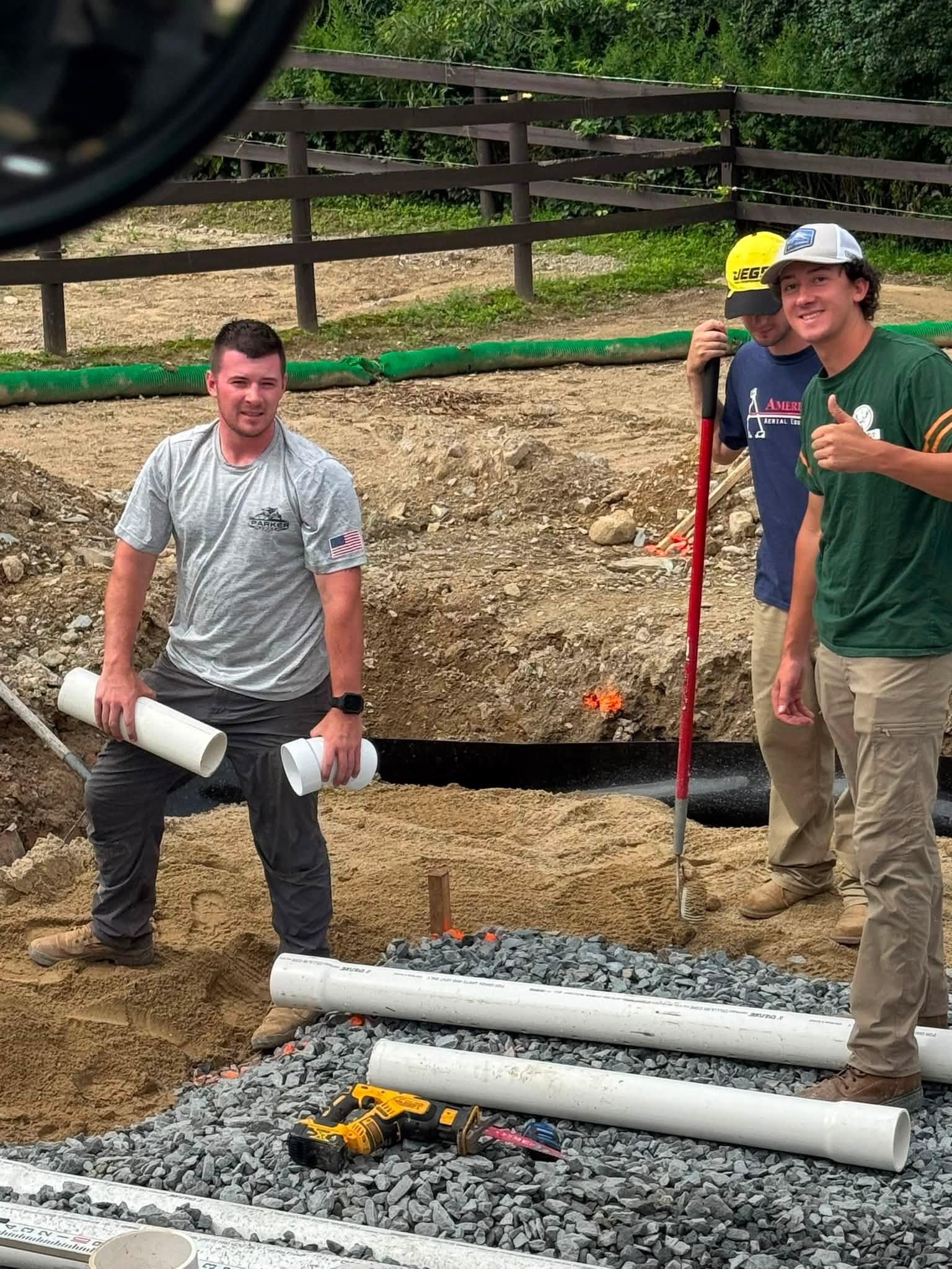 Four Parker crew members standing beside an excavation and orange excavator