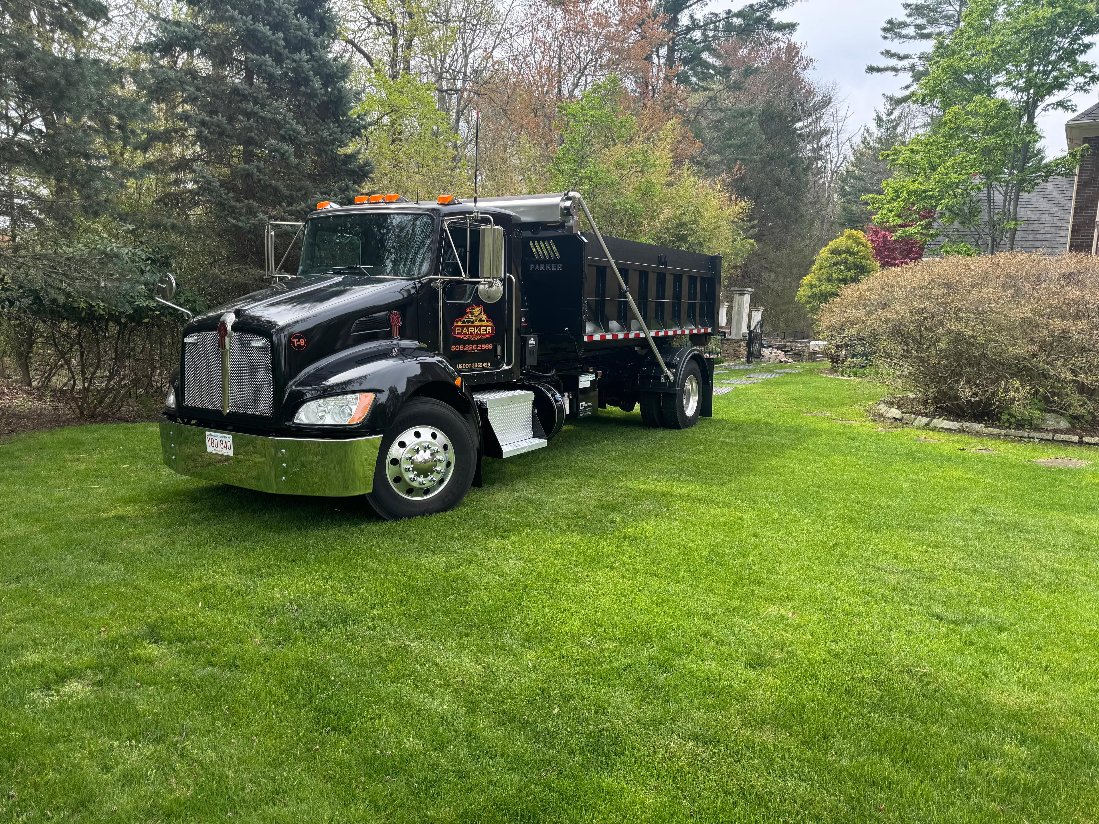 Parker & Sons dump truck parked on a residential lawn after site work