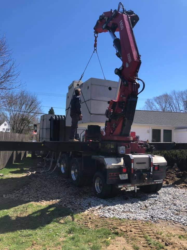 Parker crane truck setting concrete septic components at a residential site