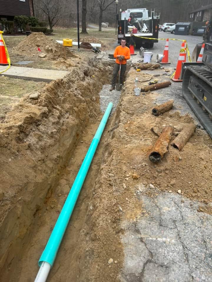 Worker standing in a prepared utility trench beside installed pipe