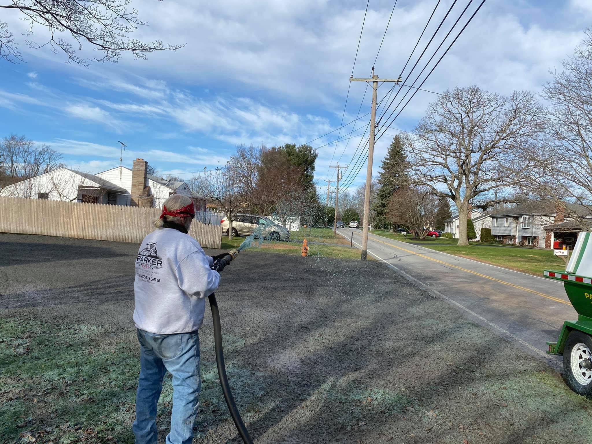 Parker crew member applying hydroseed across a prepared roadside lot
