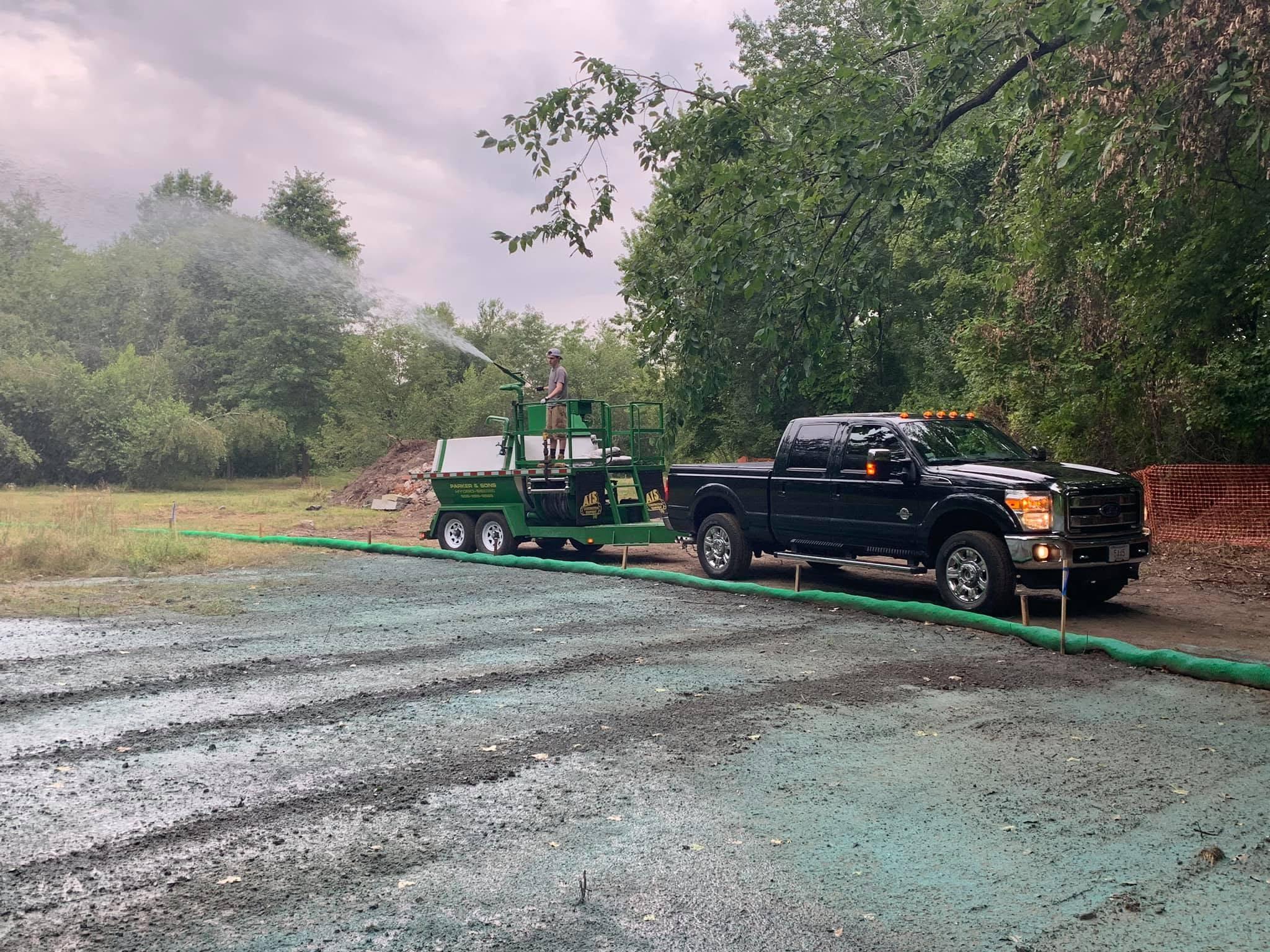 Parker operator spraying hydroseed beside a truck and trailer