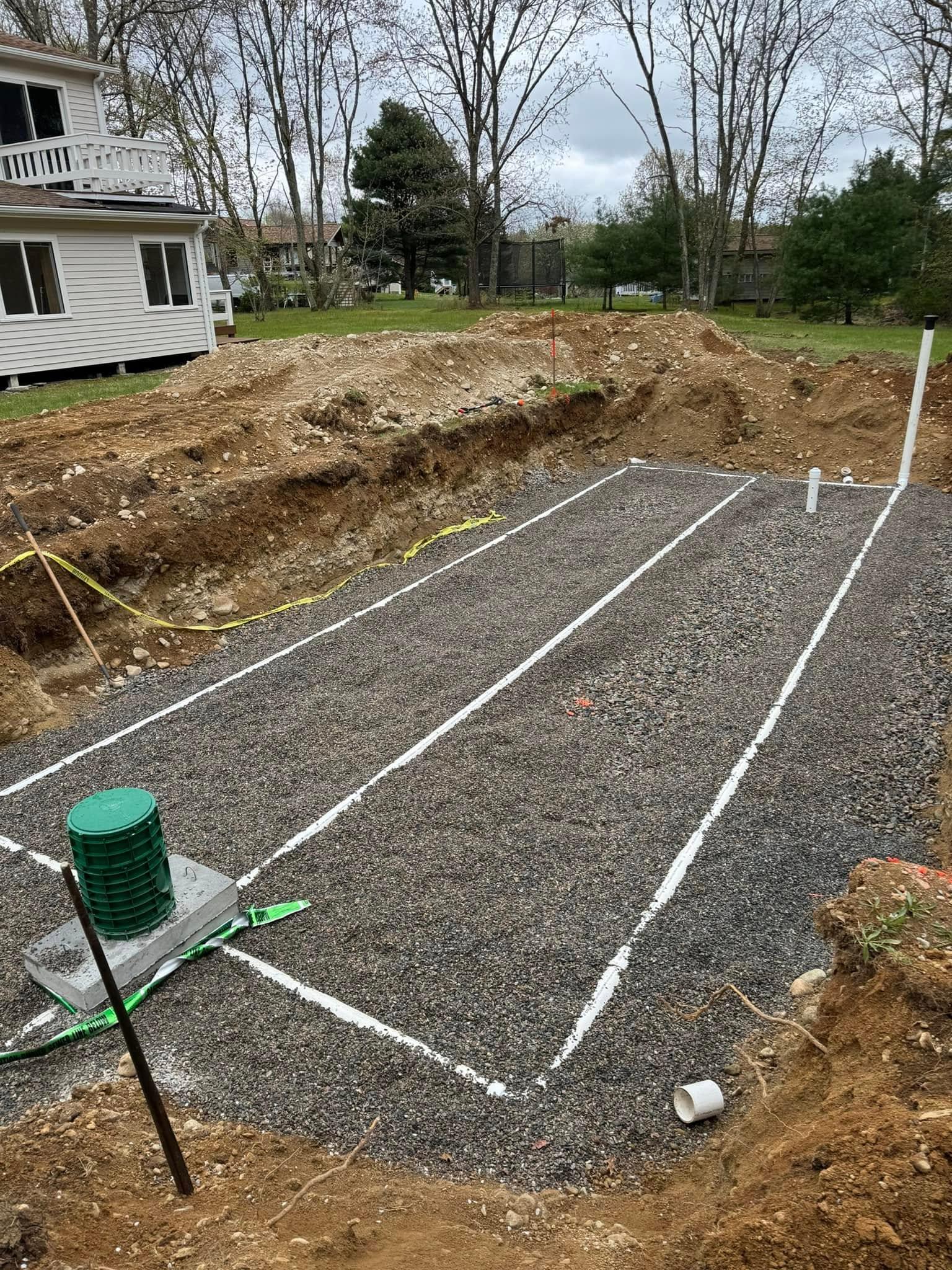 Prepared gravel septic field with marked layout lines and pipe risers