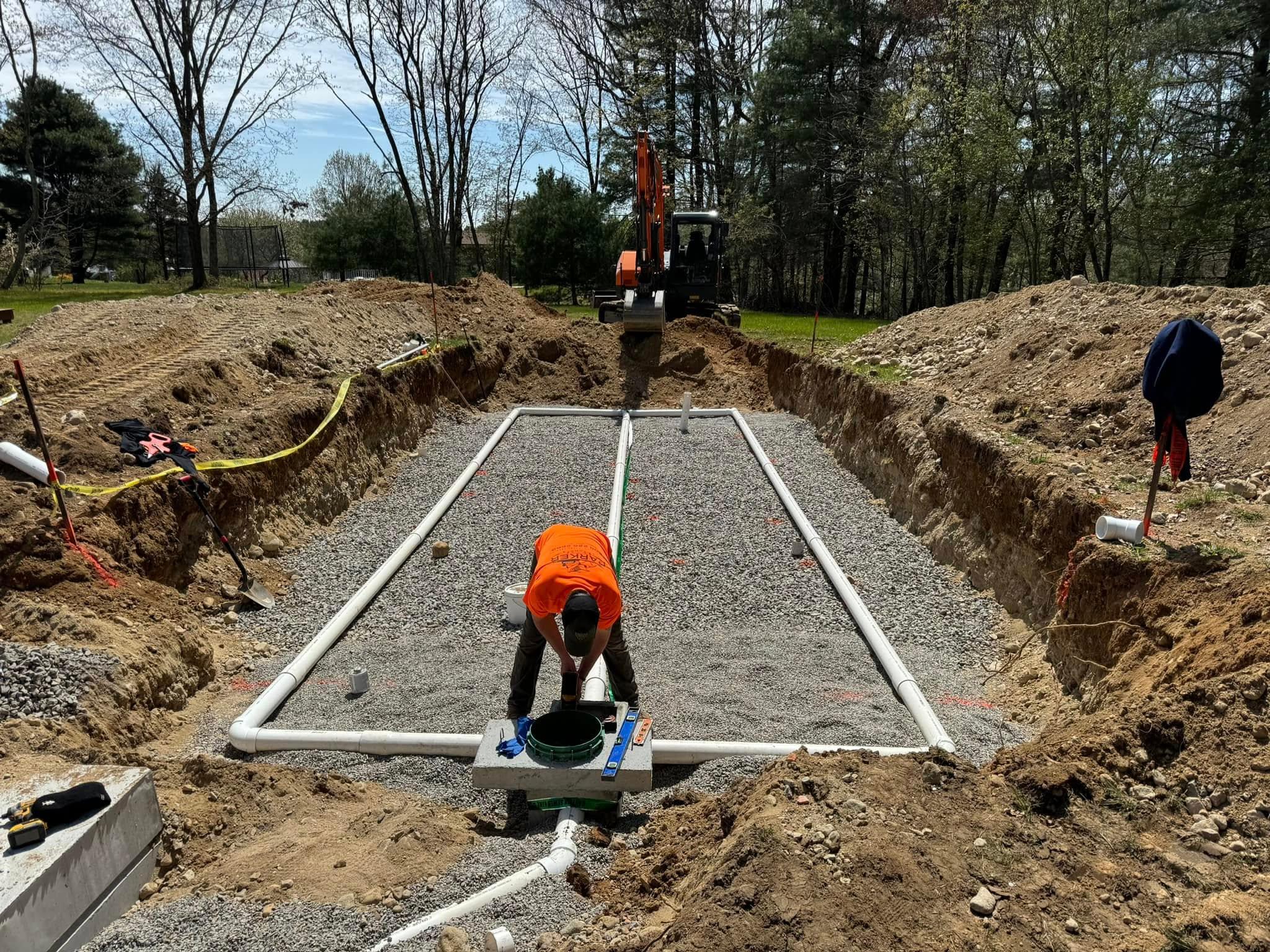 Parker crew installing distribution piping in a prepared gravel septic field